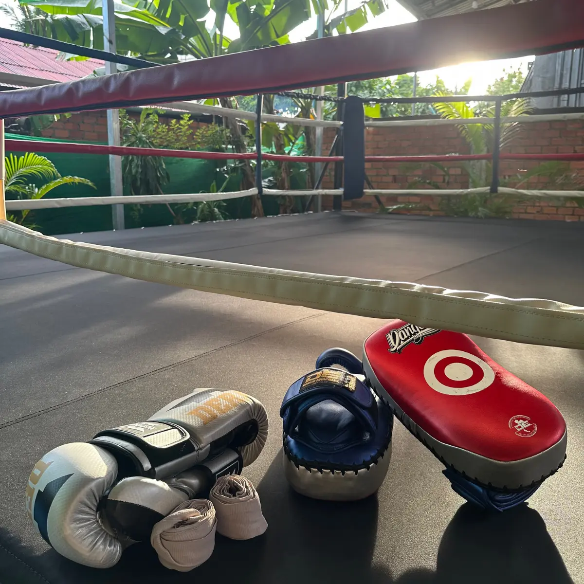 Boxing gloves, hand wraps and kick pads resting on the ring canvas.
