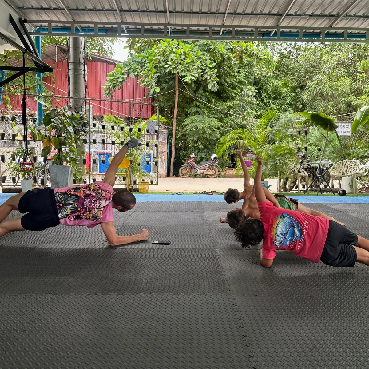 A coach and children holding one-arm planks during a finisher exercise.