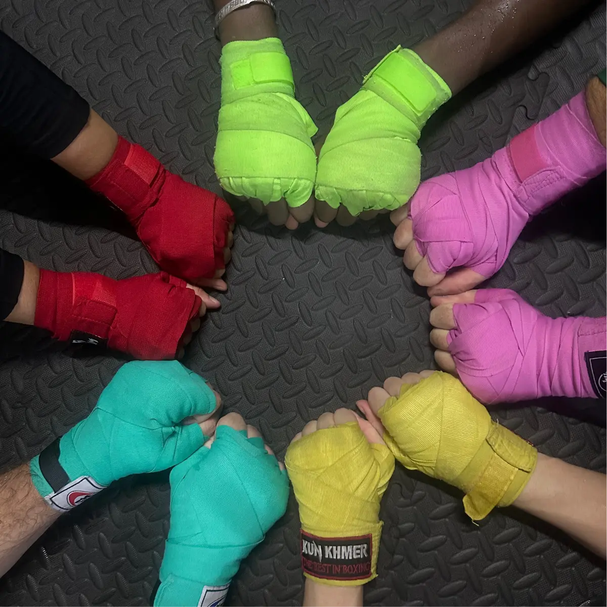 Six training partners touching wrapped hands in a circle.