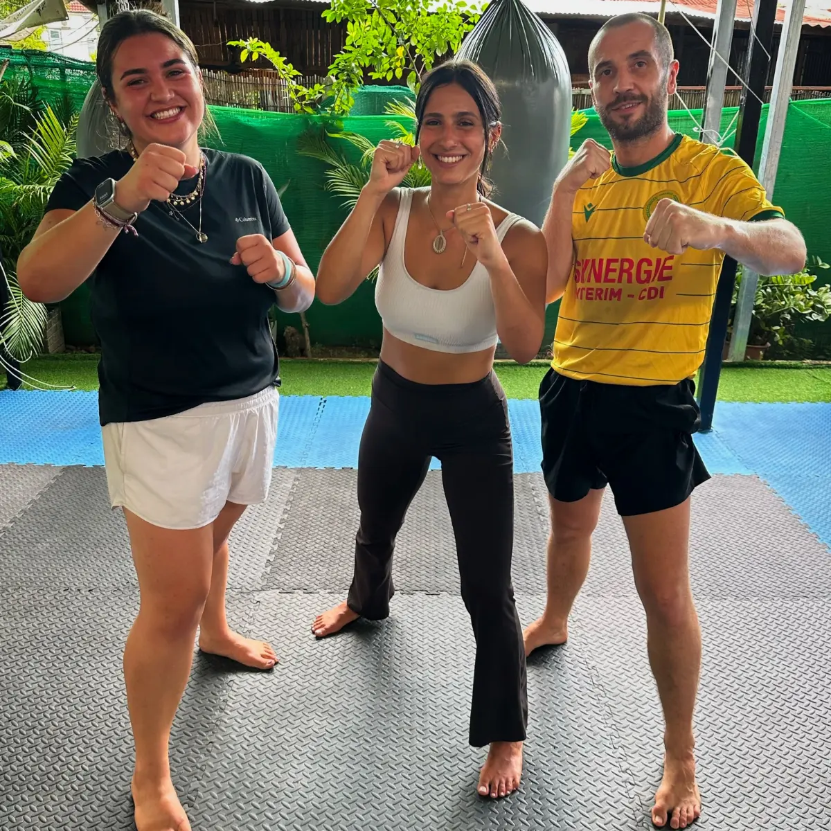 Kevin holding a boxing stance outdoors with two training partners.