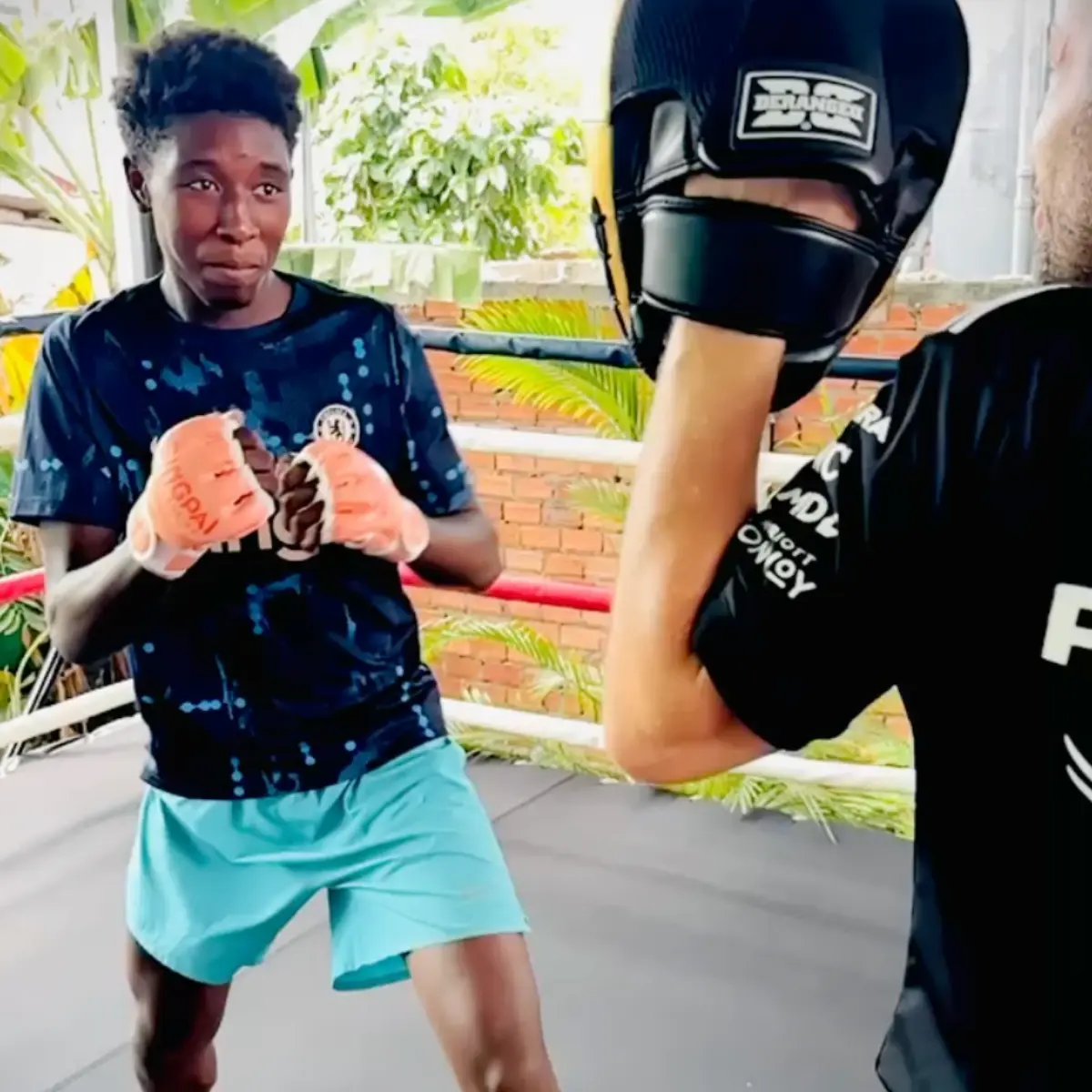 A young fighter with wrapped hands facing a partner wearing headgear.